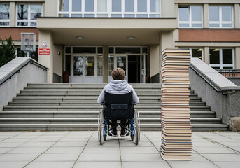 Niepełnosprawny uczeń na wózku inwalidzkim przed wejściem do szkoły 