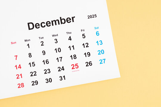Top view of December 2025 calendar with date 25 marked, Christmas celebration on light yellow background