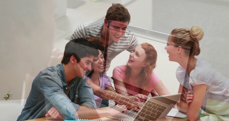 Collaborating study group typing, discussing in study lounge, with laptop, notebooks