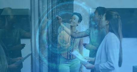 Writing lead presenter in patterned blouse marking glass partition in boardroom, with data overlay