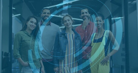 Collaborating team using blue holographic interface in open office, glass partitions and LED lights