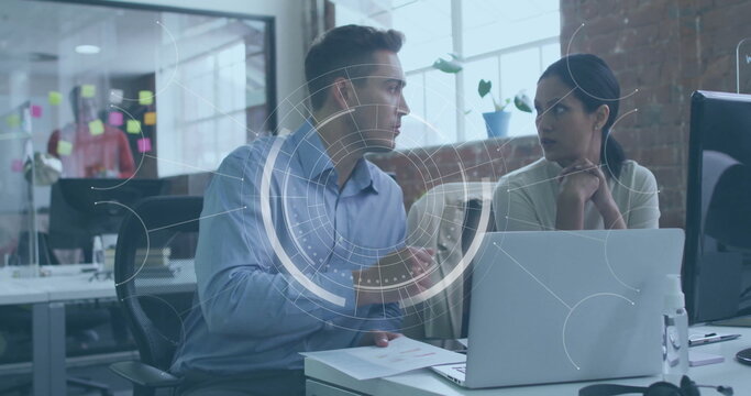 Gesturing man and listening woman discussing document on desk at open-plan office, with HUD overlay