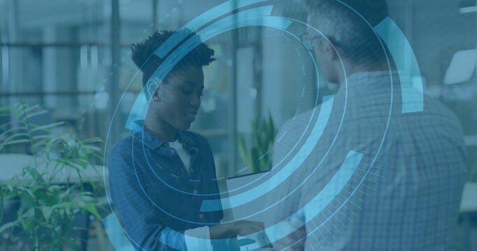 Professionals wearing button-up shirts discussing data on tablet in office, with interface overlay