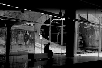 Black and white shot of lonely man sitting on the bench and waiting for train. Metro station Trindade. Porto, Portugal.