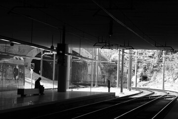 Black and white shot of lonely man sitting on the bench and waiting for train. Metro station Trindade. Porto, Portugal.
