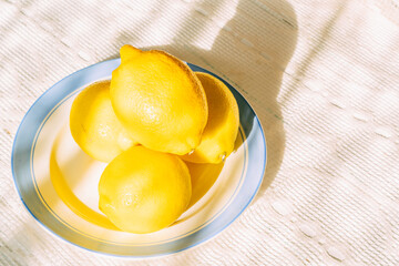 Fresh lemons on blue-rimmed plate in sunlight