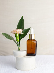 An elegant bottle in noble dark glass with natural serum and the most delicate cream to brighten your skin is decorated with an elegant flower on a plaster catwalk.