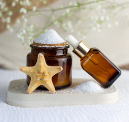 An elegant bottle in noble dark glass with natural serum and the most delicate cream to brighten your skin is decorated with an elegant flower on a plaster catwalk.