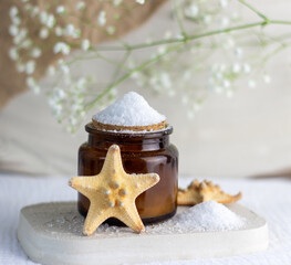 An elegant bottle in noble dark glass with natural serum and the most delicate cream to brighten your skin is decorated with an elegant flower on a plaster catwalk.