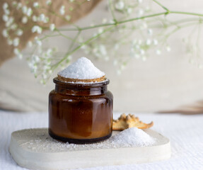 An elegant bottle in noble dark glass with natural serum and the most delicate cream to brighten your skin is decorated with an elegant flower on a plaster catwalk.