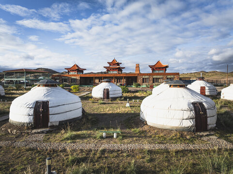 Aerial view of traditional yurts and a striking building with pagoda-style roofs stand in harmony against the Mongolian sky, Turgen, Uvs, Mongolia.