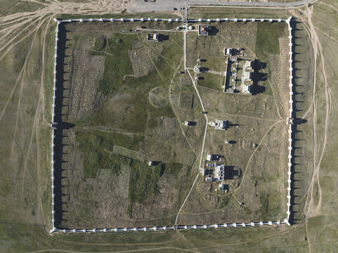 Aerial view of a square fortress with white walls enclosing buildings and open fields, a testament to historical architecture, Turgen, Uvs, Mongolia.