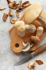 Fresh penny bun mushrooms on cutting board with knife and dried slices