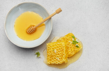 Honeycomb, honey dipper and bowl of honey on kitchen table