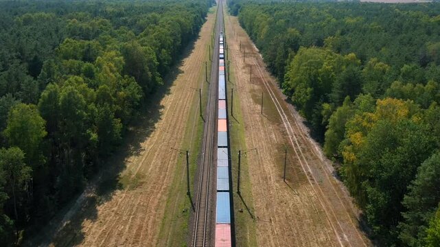 Aerial flying follow long freight train carrying containers with cargo. Transportation and delivery of goods. Railway transport travels in straight line. Cargo transportation. Export and import goods
