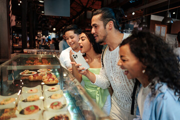 Tourists photographing food in display window at Time Out Market Lisbon