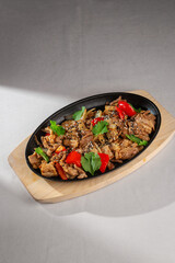Traditional Korean style grilled pork with bell peppers, onions, sesame seeds and fresh cilantro served on a sizzling hot plate over wooden board