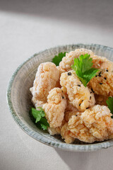 Crispy Korean chicken in a light golden crust served plain without sauce, garnished with fresh cilantro in a rustic ceramic bowl on neutral background