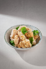 Crispy Korean chicken in a light golden crust served plain without sauce, garnished with fresh cilantro in a rustic ceramic bowl on neutral background