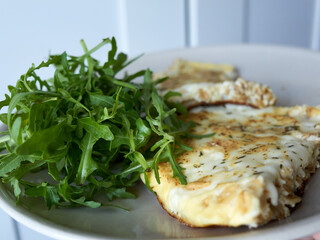 A plate of food with a piece of spinach and a piece of cheese