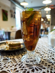 Glass of tea with a slice of lime in it sits on a table