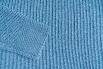 Close-up view of a light blue ribbed knit fabric material with sleeve detail and copy space of warm...
