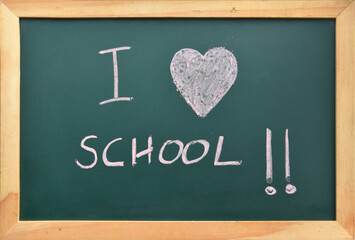 I love school hand written sign with heart in pink chalk, on blackboard with wood frame. Back to school concept. Successful student. Kids enjoying learning in school and thriving in educational system