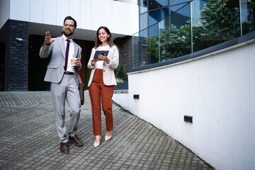 Businesspeople walking and talking in front of modern office building