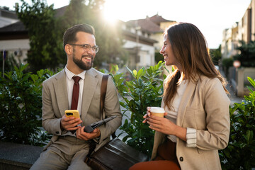 Business people talking and smiling during coffee break outdoors