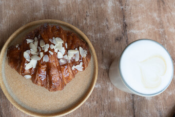 A delicious croissant sitting on a plate adjacent to a glass of milk