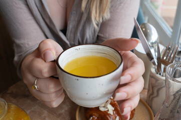 A woman is gently holding a cup filled with yellow liquid inside it
