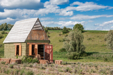 Obraz premium Beautiful wooden country house is located in a picturesque valley with hills and fields. Sky background.