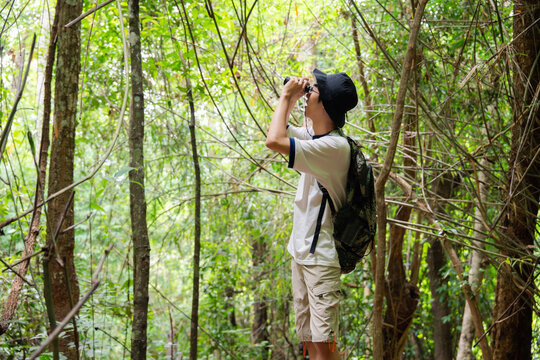 Young hiker exploring tropical forest using binoculars