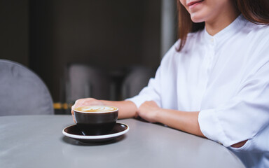 Closeup image of a woman holding a cup of hot coffee in cafe