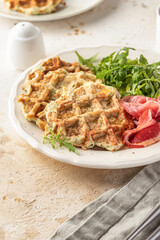 Zucchini waffles served with arugula salad and prosciutto close up. Healthy vegeterian food