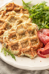 Zucchini waffles served with arugula salad and prosciutto close up. Healthy vegeterian food