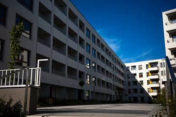 The facades of white apartment buildings against a blue sky. Modern multi-family housing.