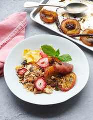 Breakfast of baked apricots and homemade granola with freeze dried fruit slices. 