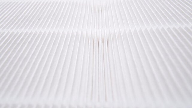 Frontal dolly-out view of white pleated air filter with symmetrical folds and soft shadows for product presentation.