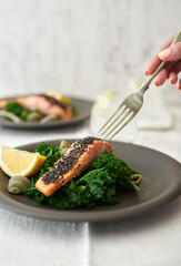Salmon fillet topped with black sesame seeds served on a bed of steamed kale.