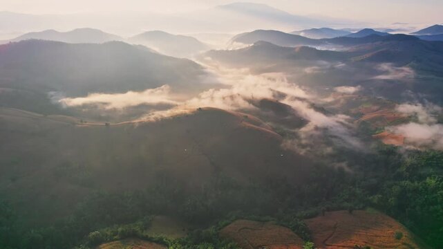 Aerial view of sunlight shines over barren deforest mountain with foggy among agricultural area in countryside at Chiang Mai, Thailand