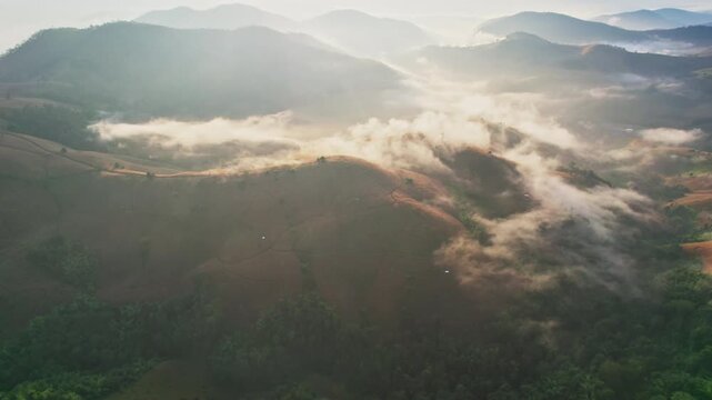 Aerial view of sunlight shines over barren deforest mountain with foggy among agricultural area in countryside at Chiang Mai, Thailand