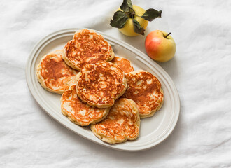 Apple fritters on an oval plate on a white background, top view