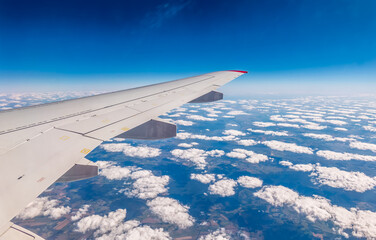 Fototapeta premium View from the airplane window at a beautiful cloudy sky and the airplane wing