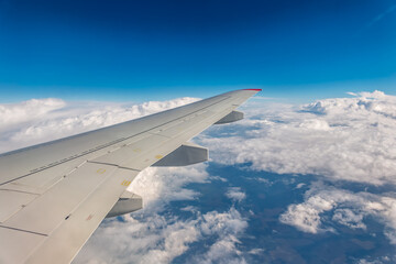 Obraz premium View from the airplane window at a beautiful cloudy sky and the airplane wing