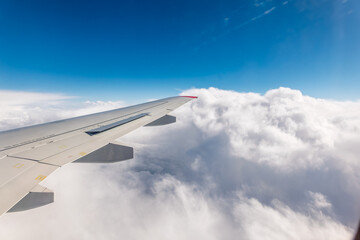 View from the airplane window at a beautiful cloudy sky and the airplane wing