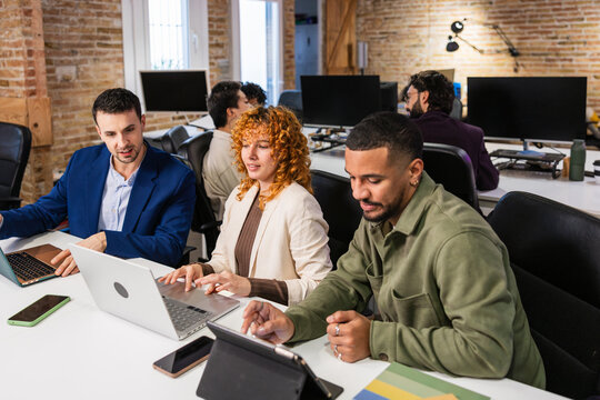 Multi ethnic team collaborating on project in modern office