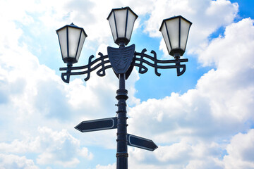 a vintage street lamp with with two directional signs pointing in opposite directions. navigation...