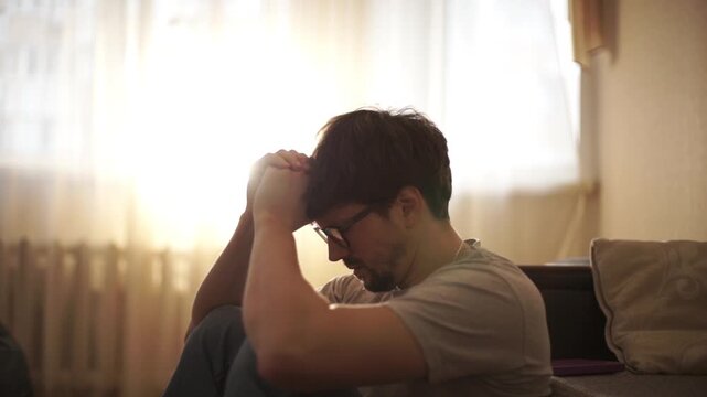 man sitting on bedroom floor and praying for divine help, asking for divine guidance during a crisis