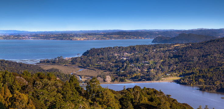 Lower Nihotupu Dam at Parau, Waitākere Ranges, Auckland region. Lake level 100% full after unusually wet July 2025. Panoramic view of Manukau Heads in distance.